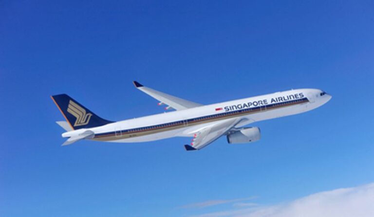 Singapore Airlines airplane in flight against a clear blue sky, white fuselage and dark blue tail with gold logo.
