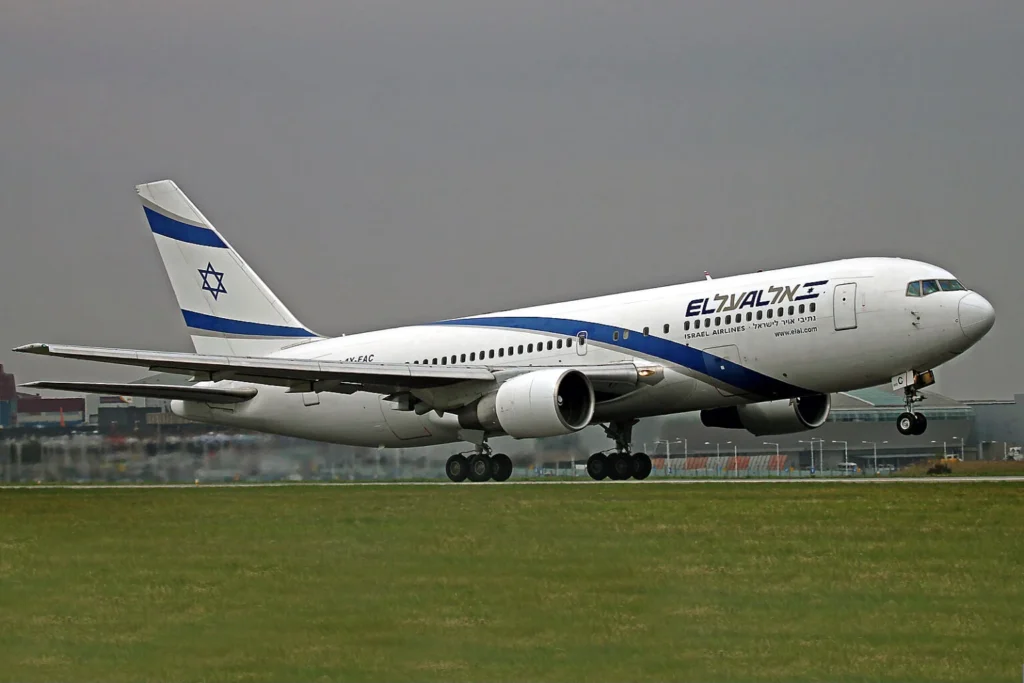 El Al passenger jet taking off from a runway with a white fuselage, blue stripe, and Star of David on the tail.