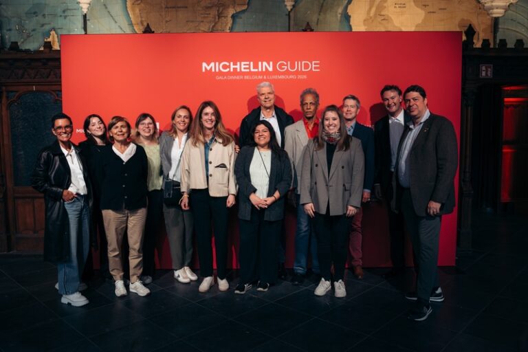 Diverse group of professionals posing together in a line in front of a red Michelin Guide backdrop at a gala dinner (Belgium & Luxembourg, 2016).