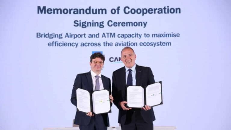 Two men in business suits hold open folders with signed documents at a Memorandum of Cooperation signing ceremony.