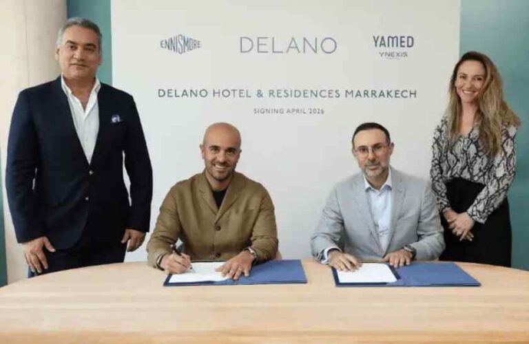 Four professionals at a signing ceremony for Delano Marrakech; two men sit and sign documents at a table while two others stand beside, backdrop shows Delano Hotel & Residences Marrakech.