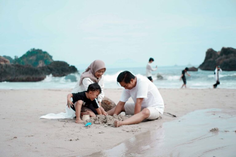 Family at the beach building a sandcastle together near the shoreline.
