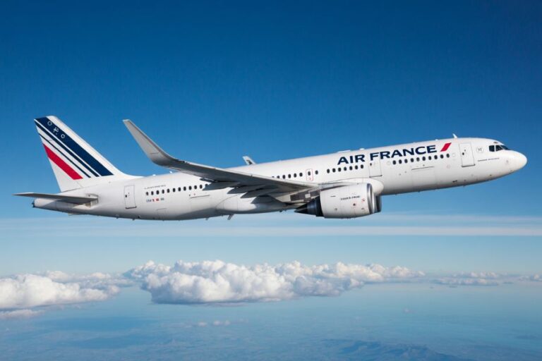 Air France commercial jet flying above fluffy clouds under a clear blue sky.