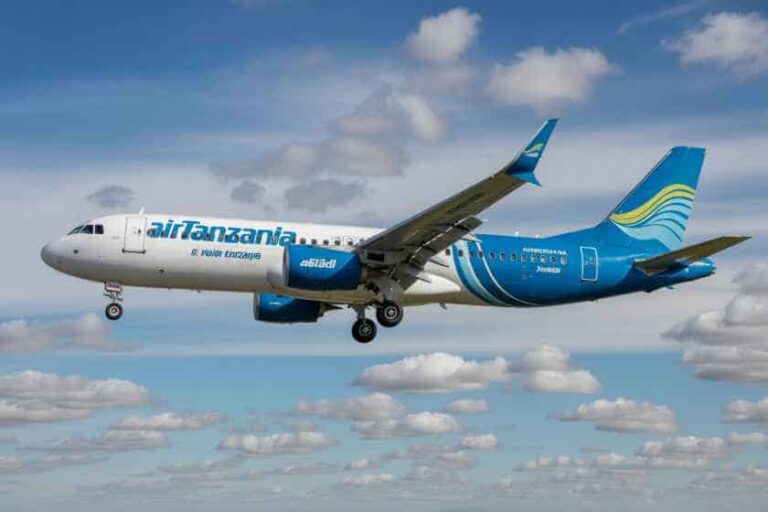 Air Tanzania passenger jet in blue livery flying in a cloudy blue sky.