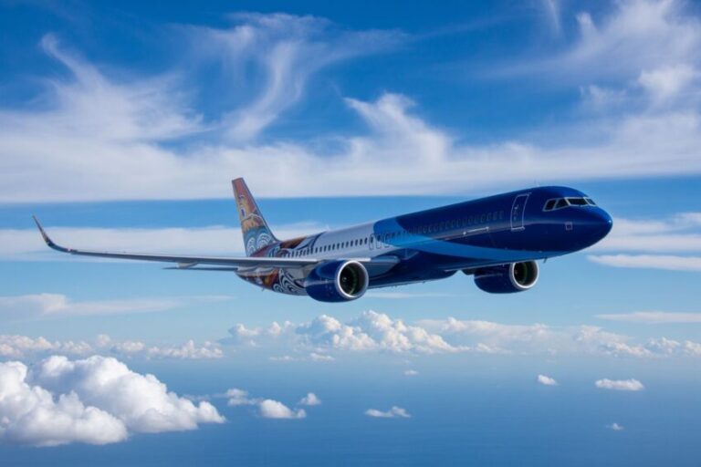 Blue commercial airplane in flight over a cloudy blue sky.