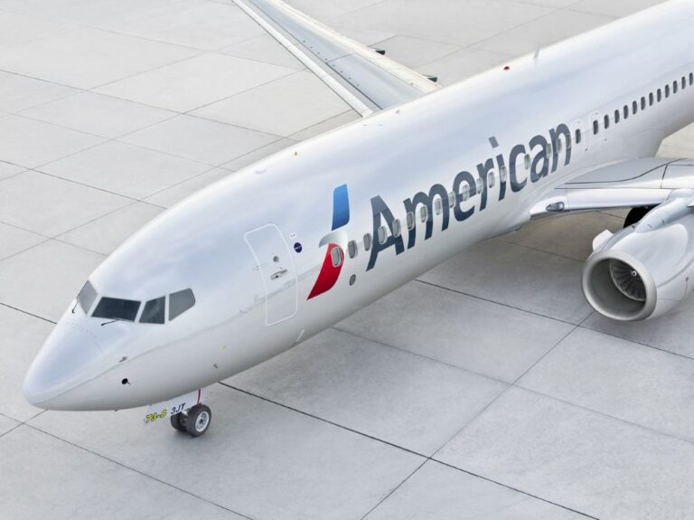 White American Airlines jet on a concrete tarmac, showing the nose, cockpit windows, and engine.