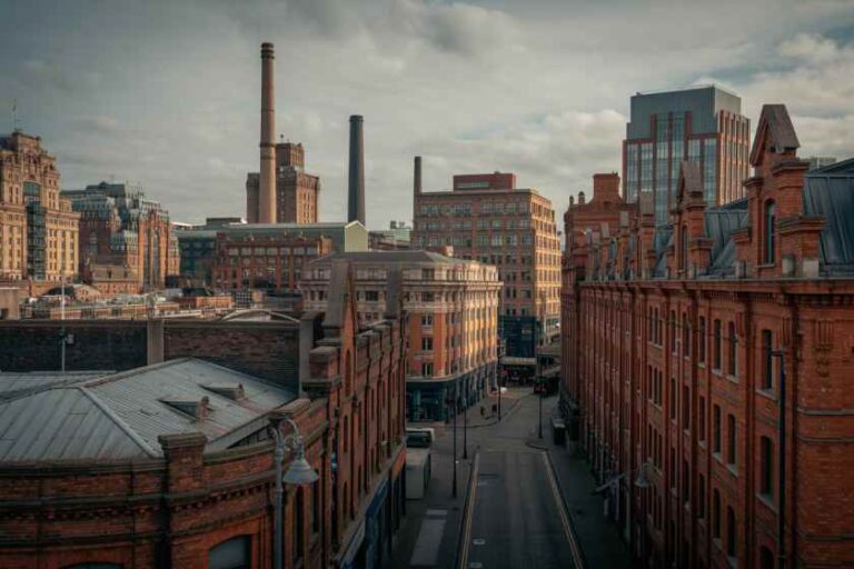 Red brick warehouse street with tall chimneys in an industrial city skyline.