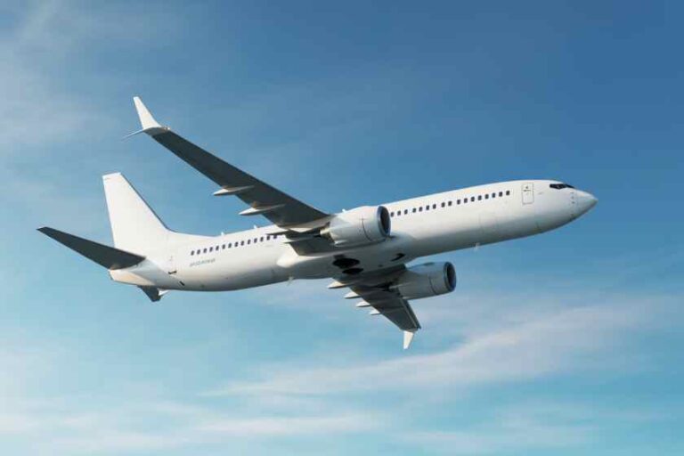White passenger jet in midflight against a clear blue sky.