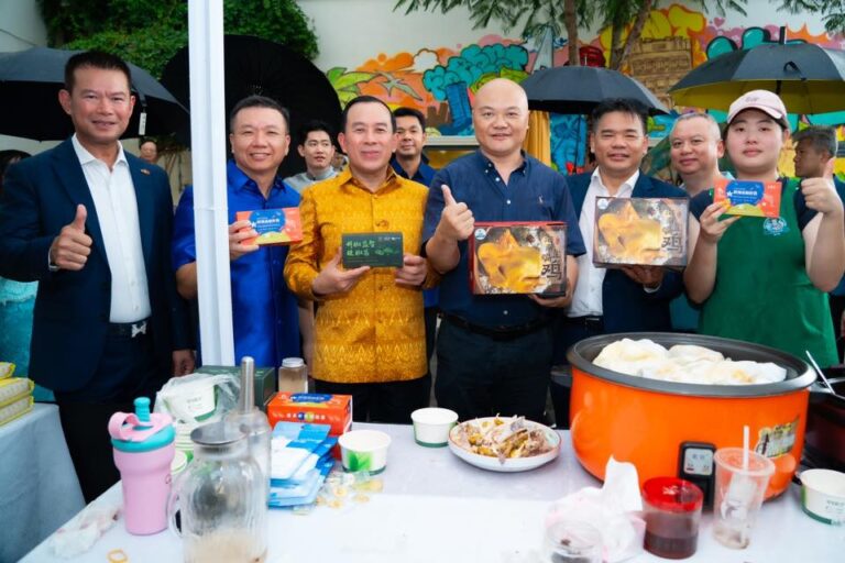 Group of people posing at a booth, holding boxed goods and smiling.