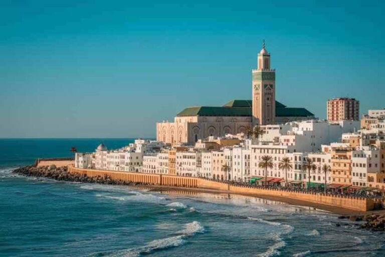 Casablanca's Hassan II Mosque along the Atlantic coast, with white buildings and palm trees lining the shore.