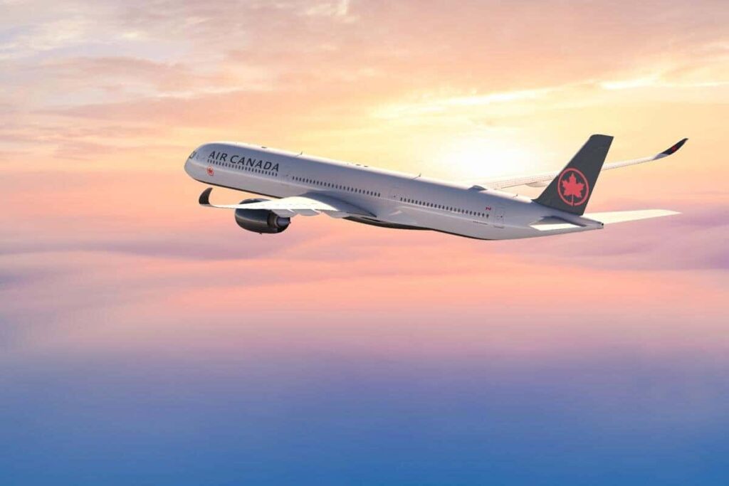Air Canada passenger jet flying above a sunset-lit sky.