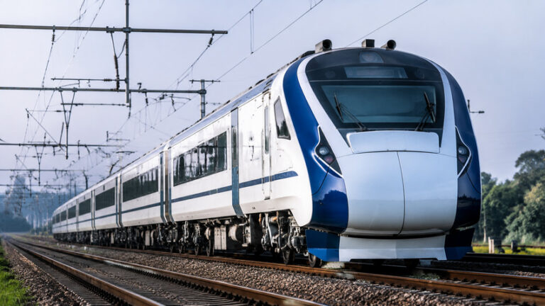 Modern white and blue electric passenger train on railway tracks with overhead power lines.