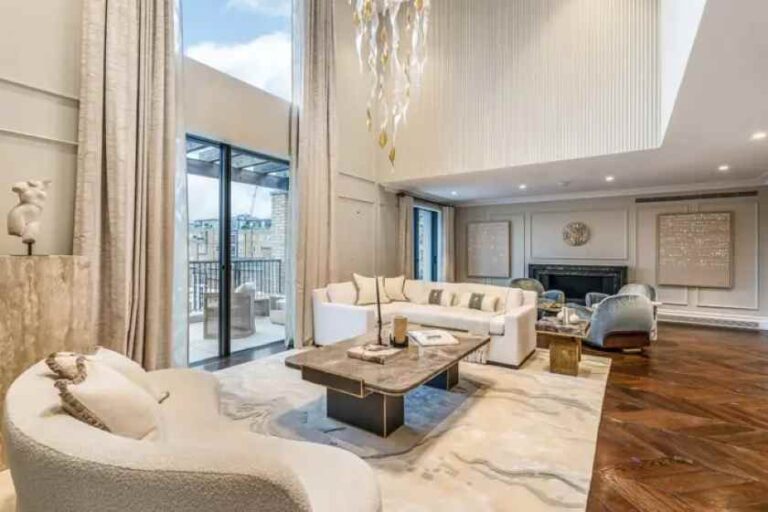 Elegant living room with white seating, a marble coffee table, and a fireplace in a bright, spacious area.