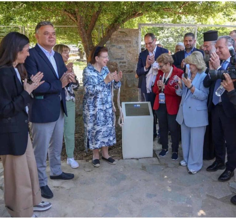 Group of people outdoors clapping around a pedestal or plaque during an unveiling ceremony.