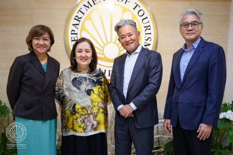 Four professionals smiling for a group photo in front of a Department of Tourism Philippines emblem.