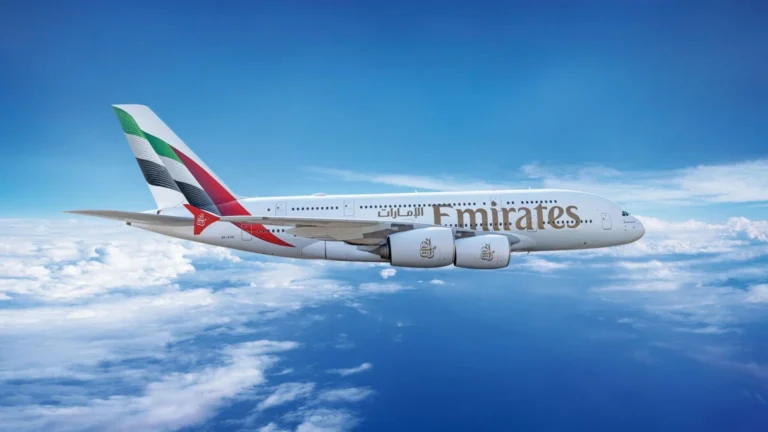 Emirates A380 airliner in flight above clouds, white fuselage with large Emirates logo and colorful tail livery