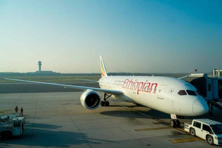 Ethiopian Airlines plane parked at a gate, jet bridge connected to the front door on the tarmac.