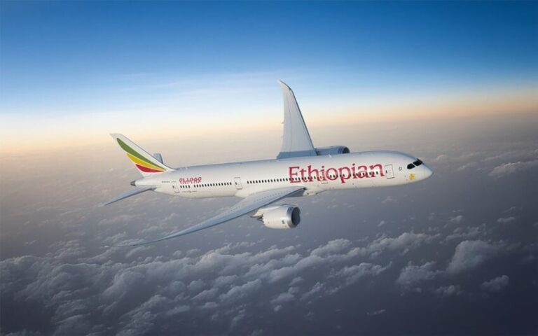Ethiopian Airlines jet cruising above the clouds at sunset in a blue sky