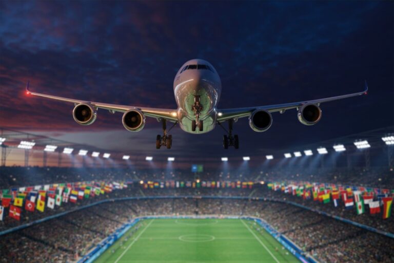 Airplane descending toward a crowded stadium at dusk with flags lining the stands and bright stadium lights above.