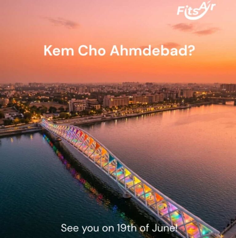 Promotional banner of a rainbow-lit bridge over a river at sunset in Ahmedabad, with the text 'Kem Cho Ahmedabad?' and 'See you on 19th of June!'