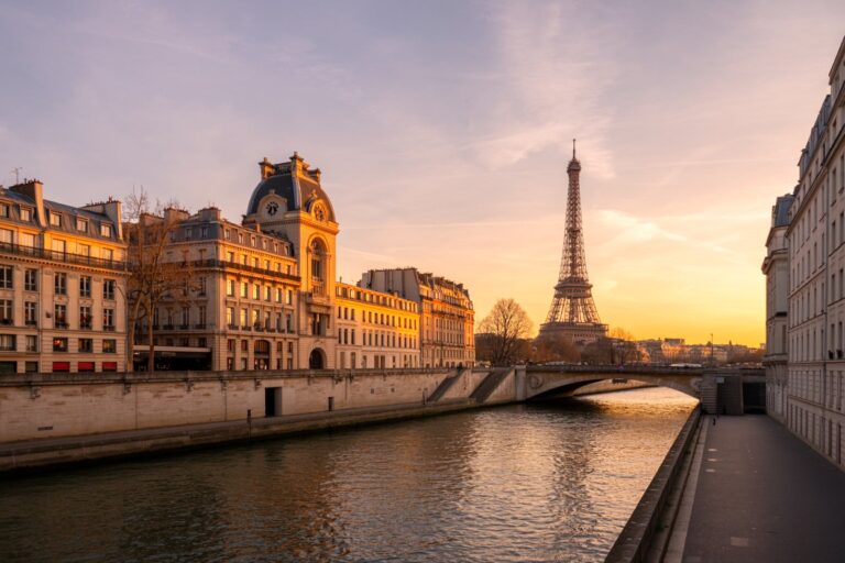 Sunset along the Seine in Paris, with Haussmannian buildings and the Eiffel Tower in the distance.