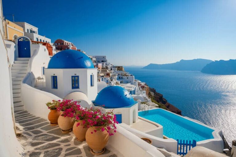 Whitewashed buildings with blue domes cascade toward the Aegean Sea in Santorini.