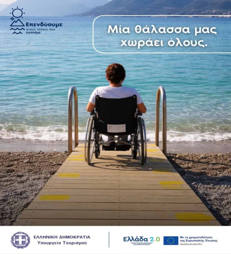 Person in a wheelchair on a wooden beach boardwalk facing the sea; banner reads 'Μία θάλασσα μας χωράει όλους'.