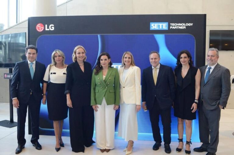 Eight businesspeople in formal attire pose for a group photo in front of an LG SETE backdrop at a corporate event.