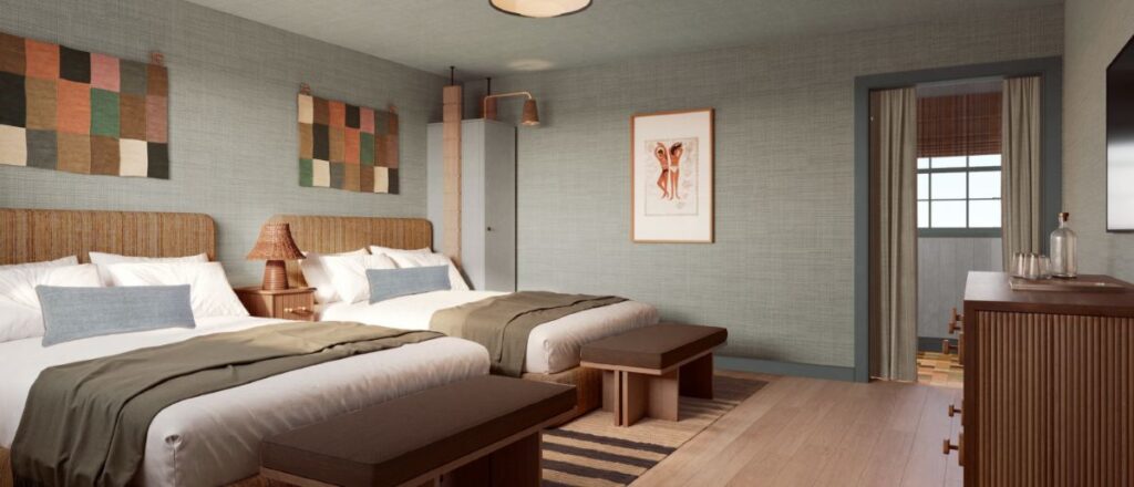Hotel room with two queen beds, wooden benches, and a dresser; olive-green walls and abstract art on the walls.