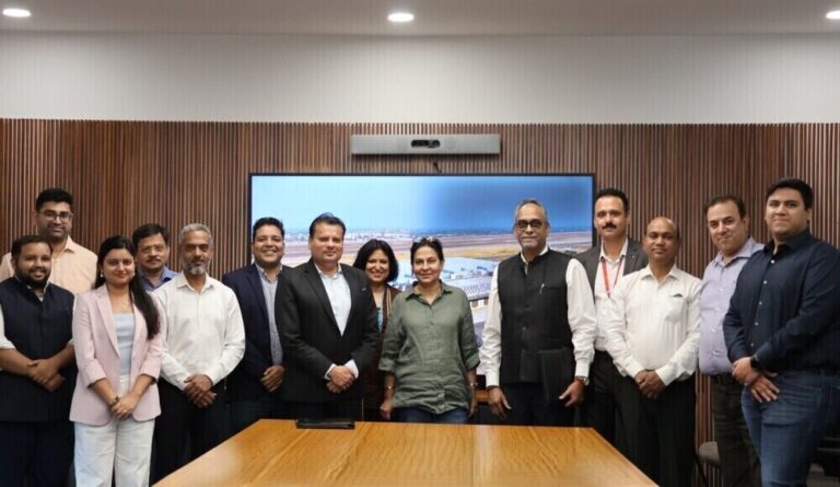 Group of professionals posing for a photo in a conference room with a large screen on the wall behind them.