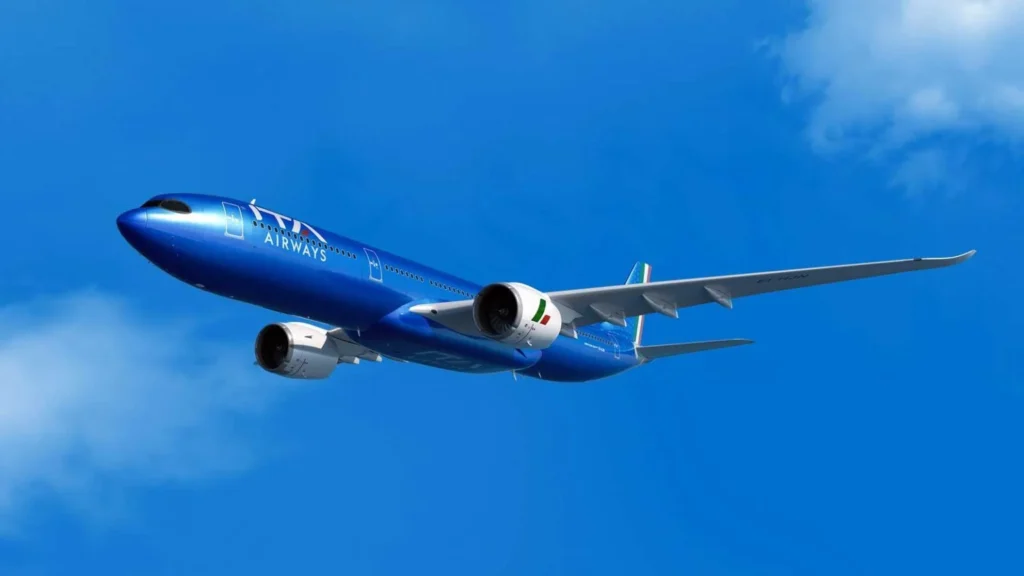 Blue commercial jet in flight with two engines visible against a clear blue sky, left-side perspective and wings extended to the right.