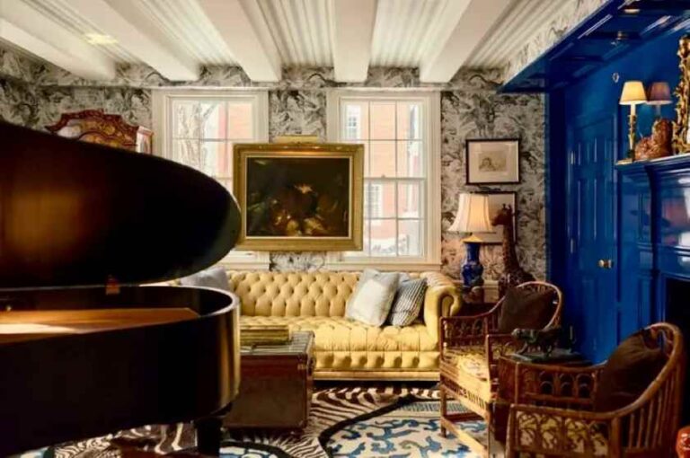 Luxurious living room with a grand piano in the foreground, a tufted yellow sofa, patterned wallpaper, and a blue paneled wall.