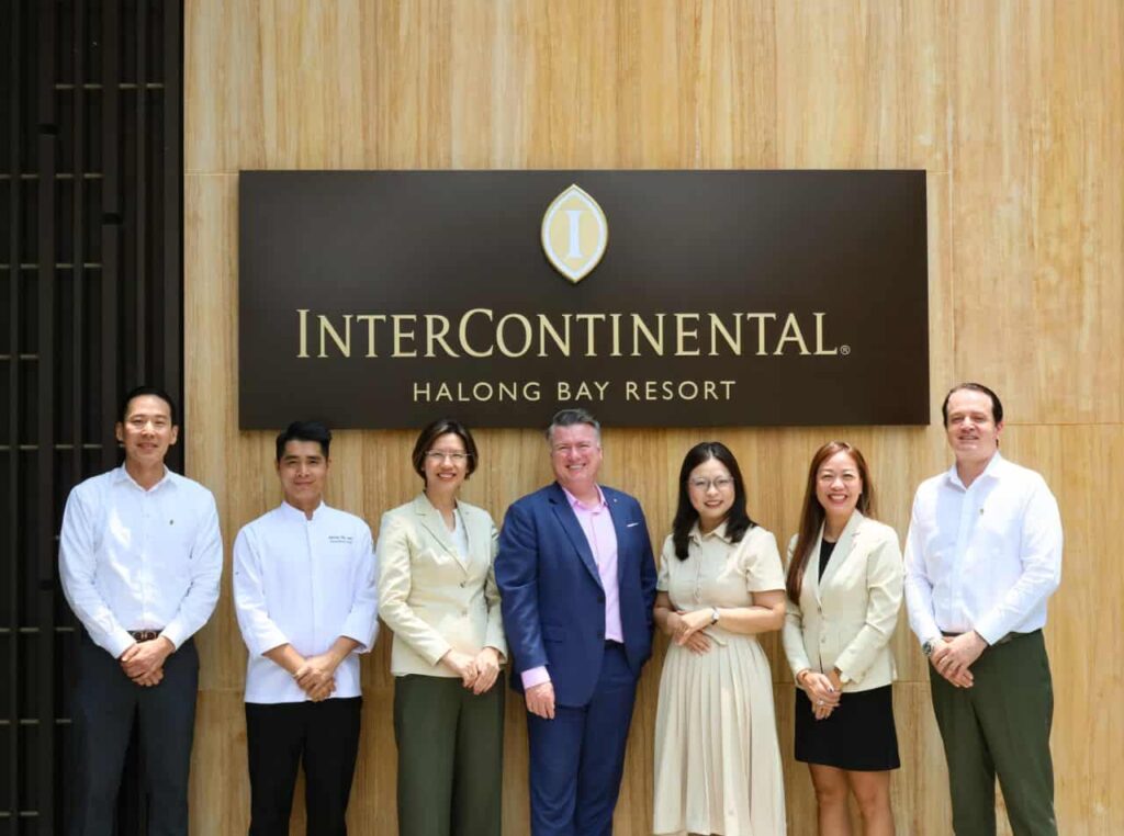 Seven professionals pose for a photo in front of a wood-paneled wall and a large InterContinental Halong Bay Resort sign.