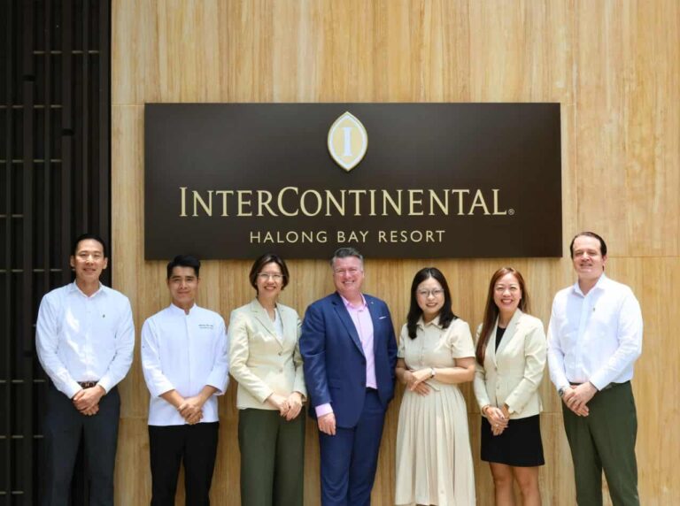 Seven professionals pose for a photo in front of a wood-paneled wall and a large InterContinental Halong Bay Resort sign.