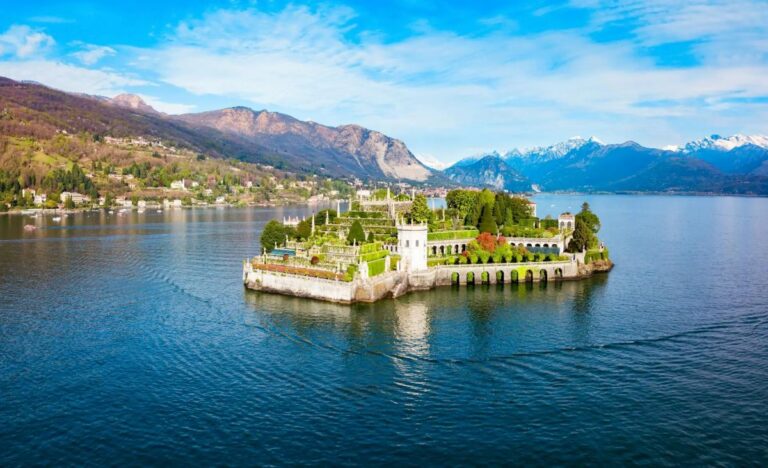 Isola Bella on Lake Maggiore, Italy: a small island with tiered formal gardens, a white villa, and arched corridors surrounded by blue water and distant mountains.
