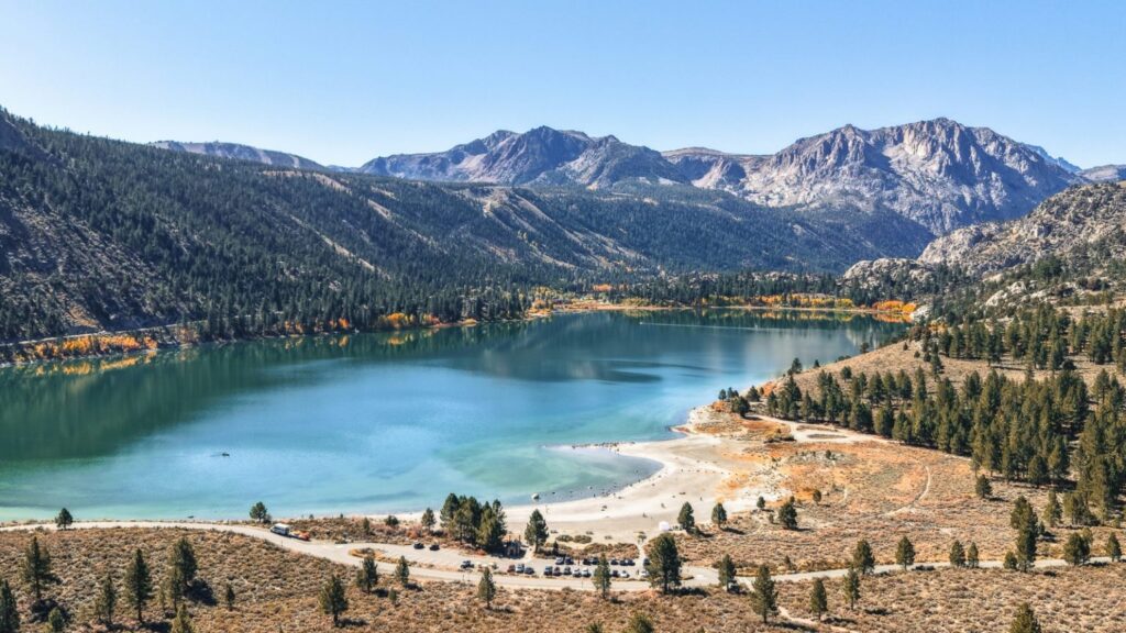 Turquoise alpine lake surrounded by pine forests and rugged mountains under a clear blue sky