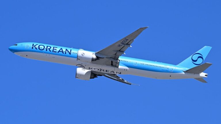 Side view of a Korean Air jet in light blue livery flying against a clear blue sky