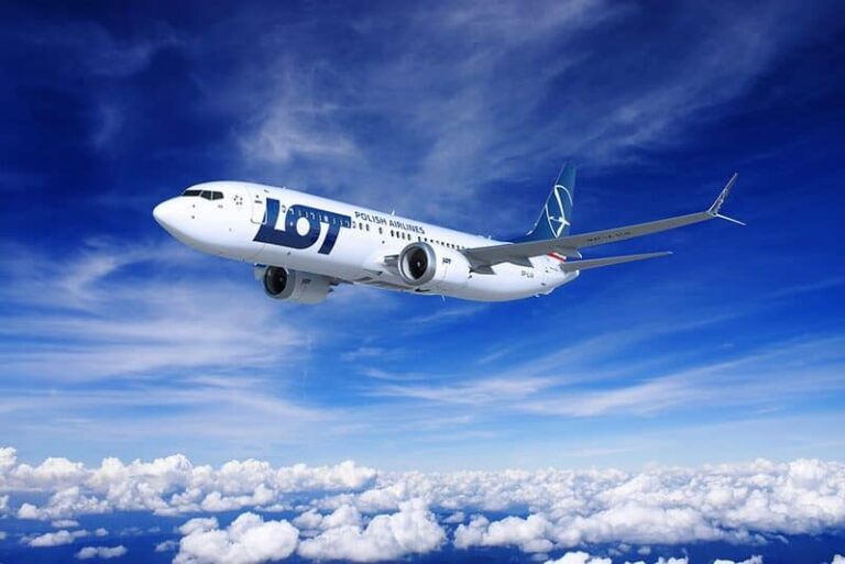 LOT Polish Airlines passenger jet flying above white clouds against a deep blue sky.