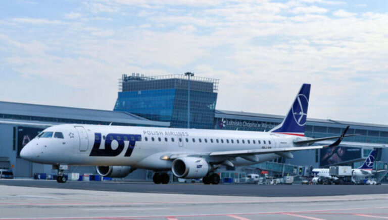 LOT Polish Airlines plane parked at the gate by a modern airport terminal, ready for boarding.