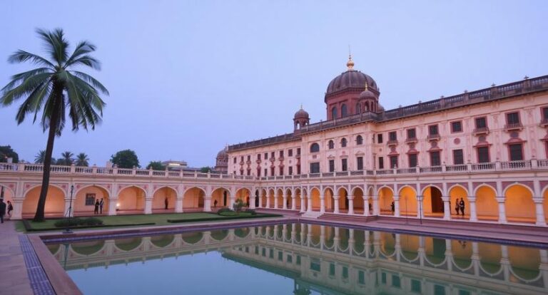 Palm tree beside a grand palace with an arched colonnade and a reflecting pool in the courtyard at twilight.