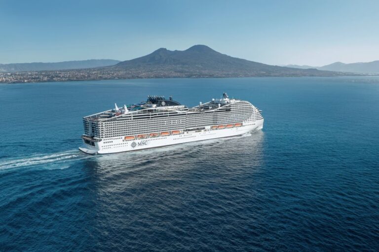 Large white MSC cruise ship sailing on calm blue sea with a mountainous coastline in the background.