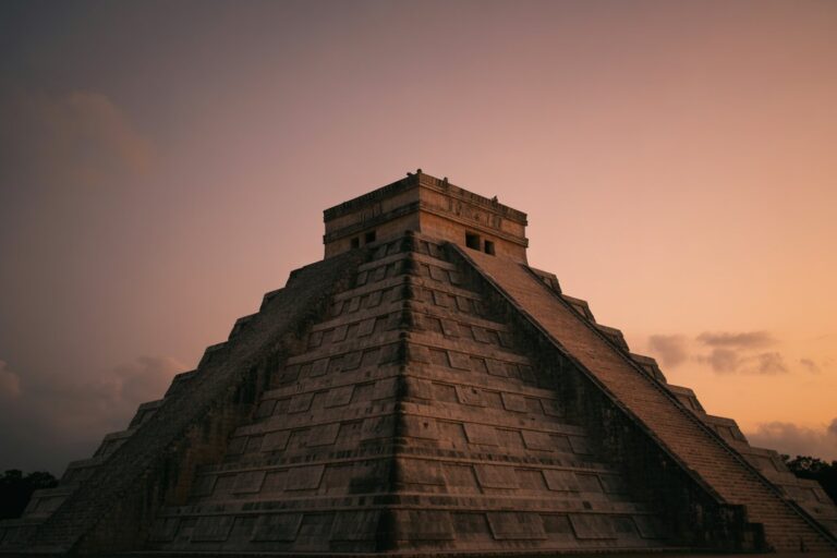 Mayan pyramid with wide stepped terraces at sunset, central staircase on the right side of the structure.