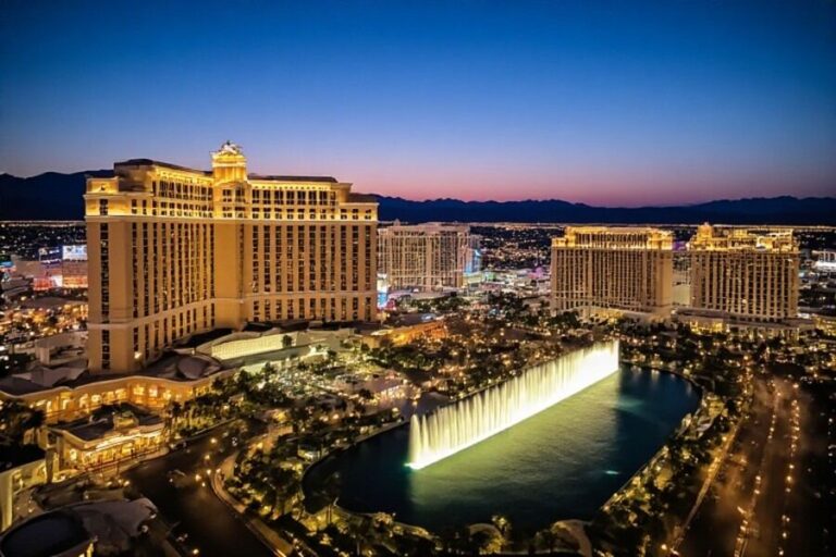 Aerial view of the Bellagio hotel and its illuminated fountains along a lake at dusk in Las Vegas, Nevada.