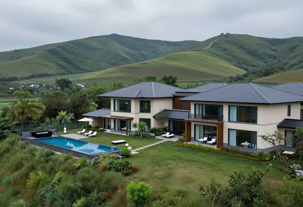 Modern villa with gray-tiled roofs, a rectangular pool, and a manicured lawn set against rolling green hills in the distance.