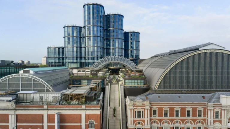 Cluster of blue glass office towers with a curved glass walkway/atrium and elevated terraces in a city-center complex.
