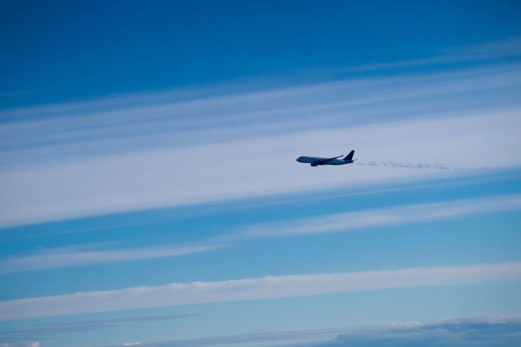 Airplane flying high in a clear blue sky with a faint contrail behind it .
