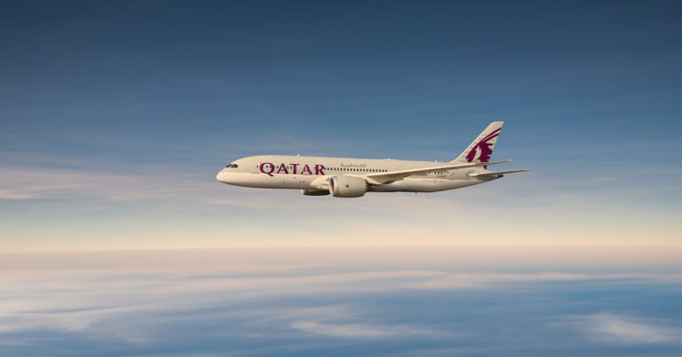 Qatar Airways airliner in white with maroon logo, flying above a cloudy horizon at altitude.