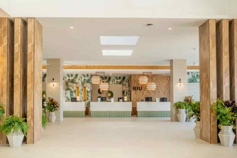Hotel lobby with a bright reception desk area and tropical plants for a welcoming check-in experience at RIU