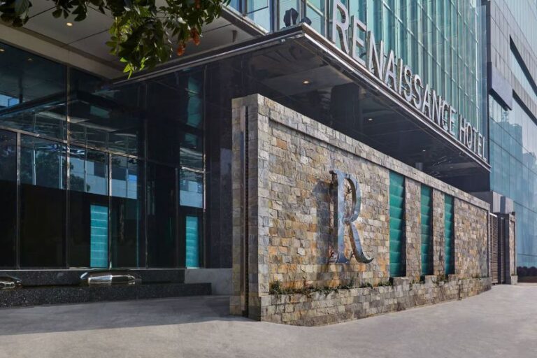 Exterior view of a Renaissance Hotel with a stone wall and a large decorative 'R' logo near the entrance.
