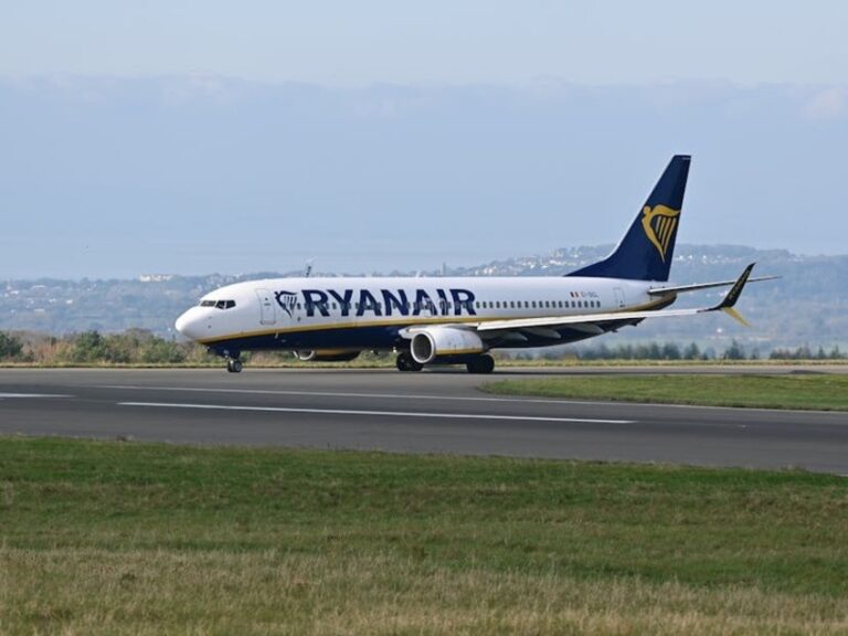 Ryanair passenger jet taxiing on the runway with a blue tail and harp logo
